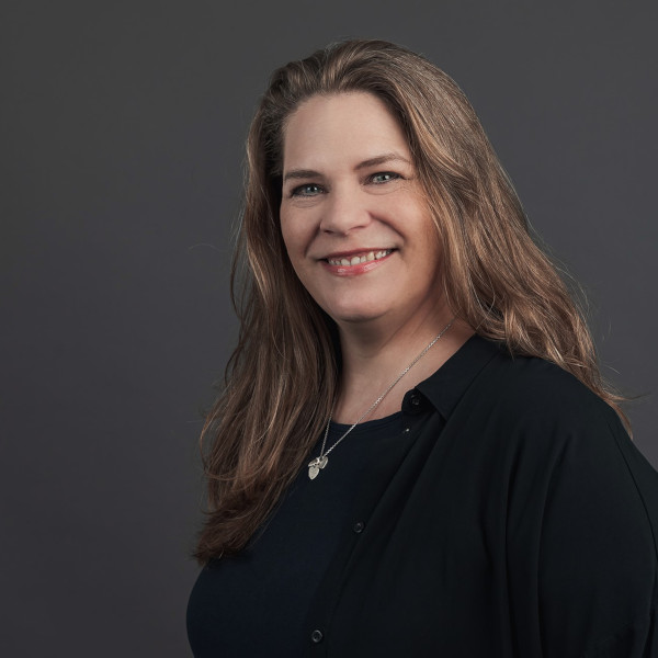 anke dahnke, management- und team-assistentin bei friederbarth, porträtfoto mit langen, gewellten haaren und dunklem oberteil