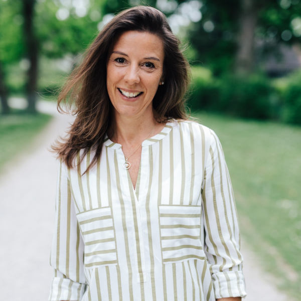 Daniela Pitzer im weiß-grün gestreiften Hemd mit Brusttaschen – Portraitaufnahme mit unscharfem Gesicht auf einem Weg im Grünen
