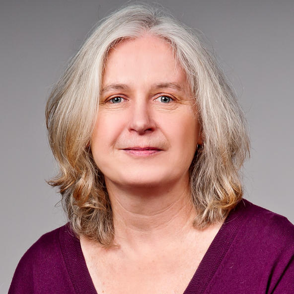 Sigrid Varduhn mit schulterlangem grauem Haar im lila Oberteil – Portraitaufnahme mit unscharfem Gesicht