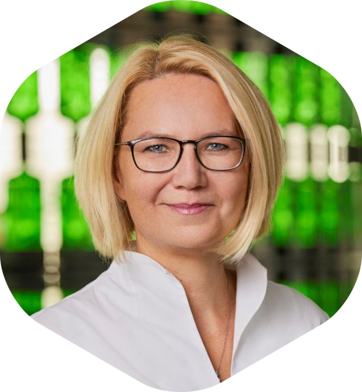 Person mit blondem Haar und weißem Hemd vor grün-schwarzem Hintergrund – symbolisch für kreative und spielerische Leadership-Formate bei Mast Jägermeister SE.