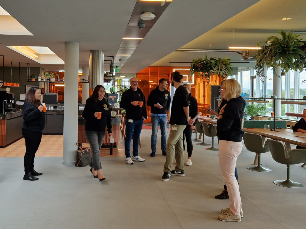 Menschen in einem modernen, lichtdurchfluteten Lounge-Bereich im Gespräch während eines Workshops bei Mast Jägermeister – freundliche Atmosphäre mit Pflanzen und Getränken.