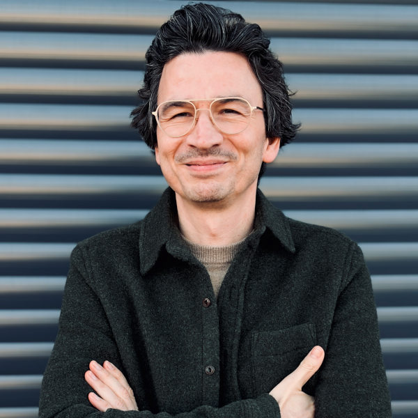 Roberto Isberner, Professional Partner und Kommunikationstrainer, mit verschränkten Armen vor modernem urbanen Hintergrund für die FRIEDERBARTH Teamseite.