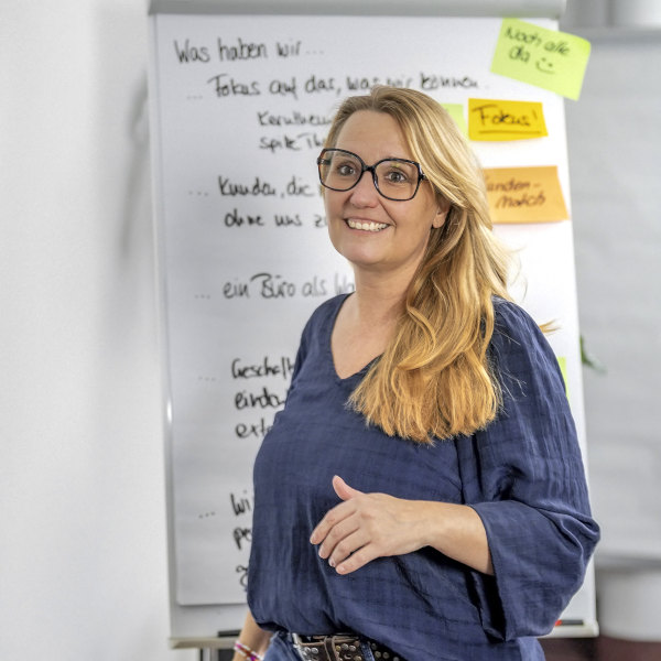 Person vor einem beschrifteten Flipchart mit farbigen Haftnotizen.
